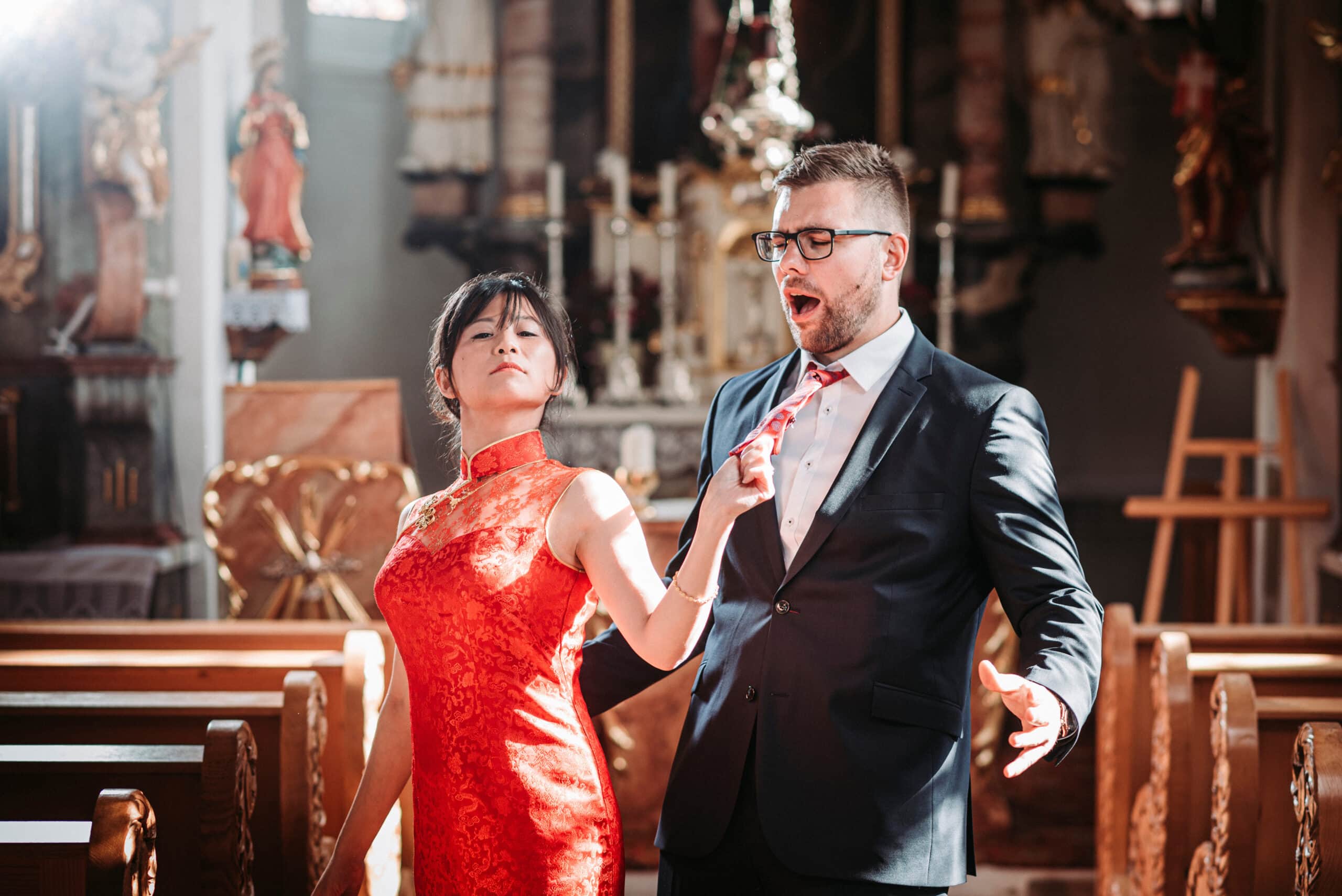 Die Braut zieht ihren Bräutigam an der Krawatte in der Kirche Mariä Heimsuchung bei Aindling auf dem Spaß-Foto.