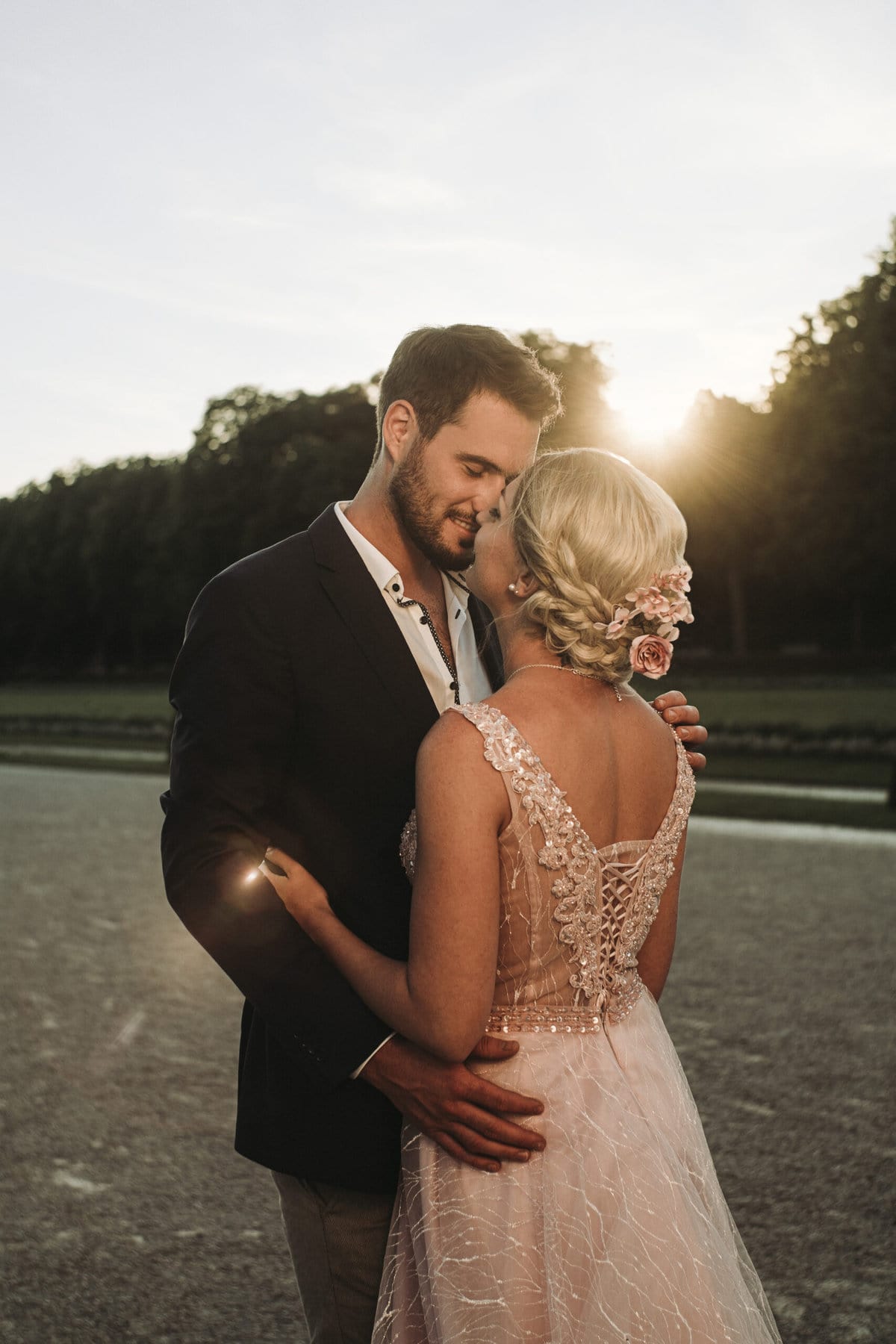 Das Brautpaar ist kurz vor einem Kuss im Sonnenuntergang im Park von Schloss Nymphenburg in München.