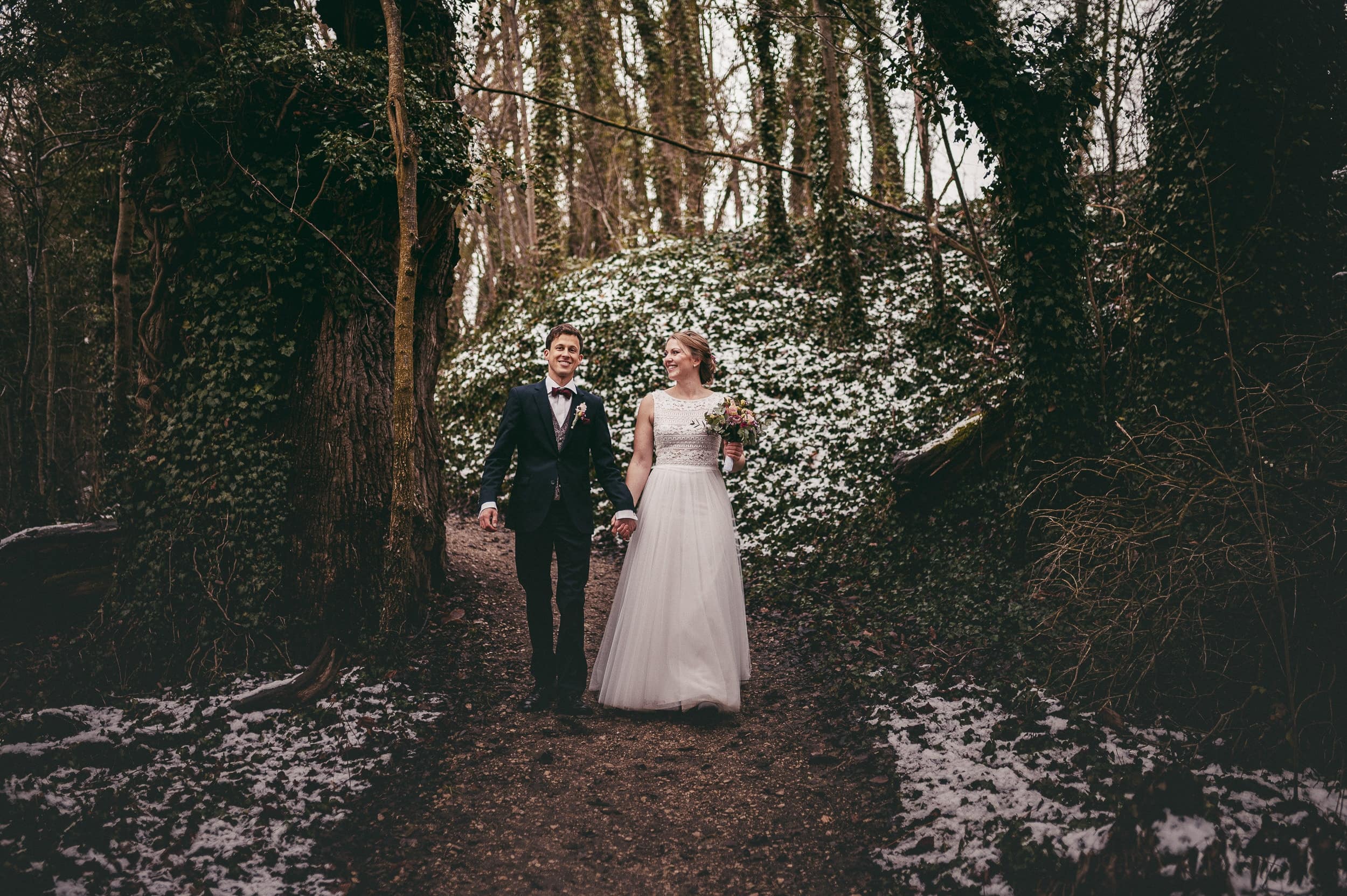 Das Brautpaar geht im verschneiten Wald in Thierhaupten spazieren.