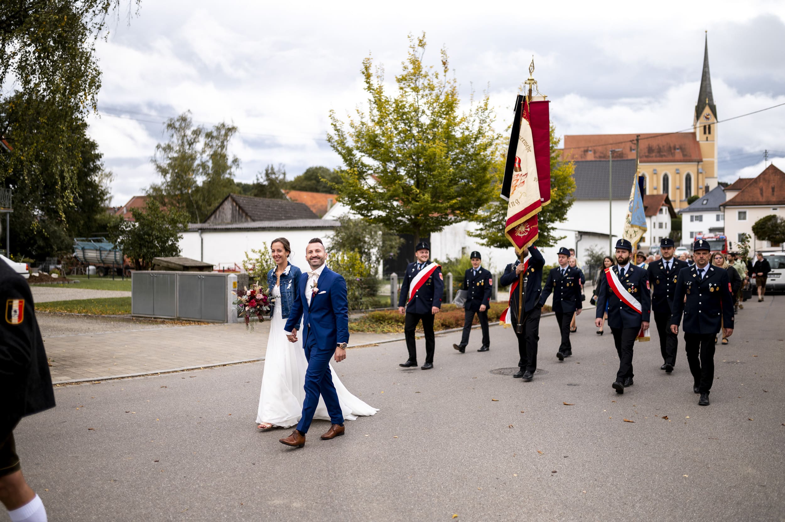Das Brautpaar läuft bei Hochzeitszug von Kirche Aindling zum Wirtshaus Moosbräu.