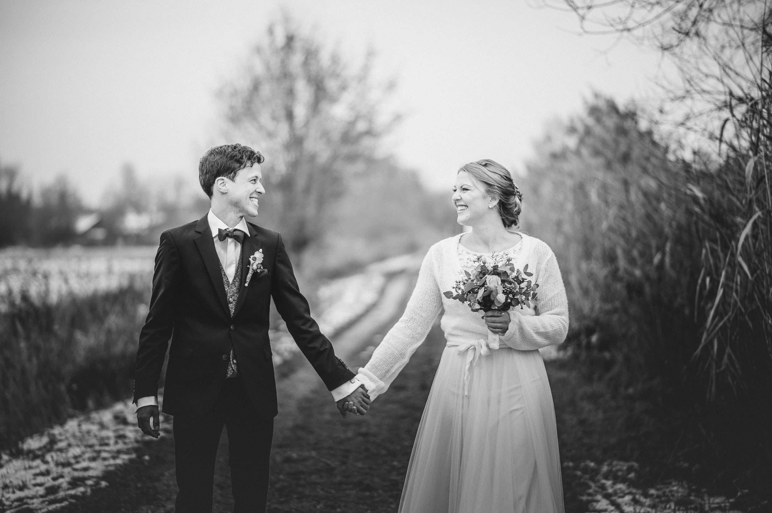 Eine Aufnahme in schwarz-weiß. Das Brautpaar lächelt sich beim Brautpaarshooting am Klosterweiher in Thierhaupten an.