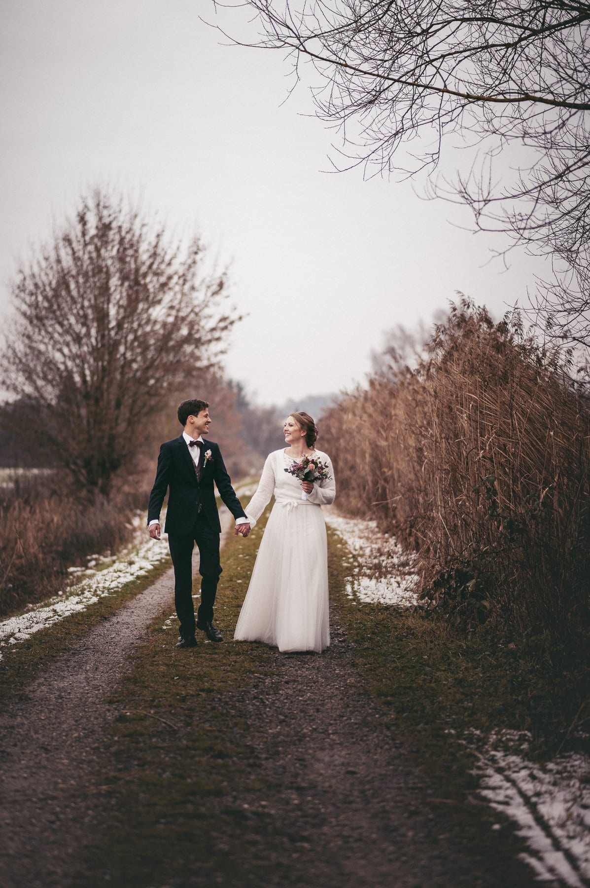 Das Brautpaar läuft und lächelt beim Hochzeitsshooting am Klosterweiher in Thierhaupten.