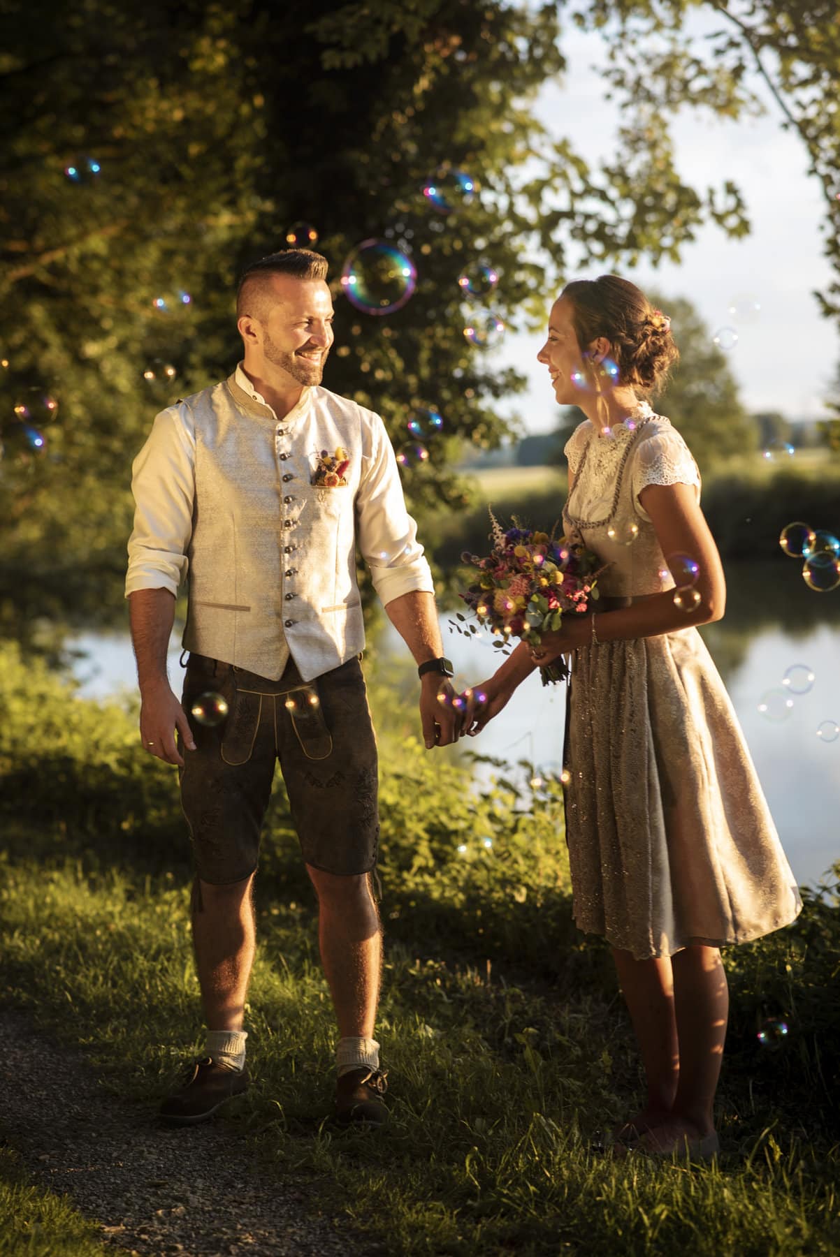 Das Brautpaar beim Hochzeitsshooting an einem See in Thierhaupten, umgeben von Seifenblasen.