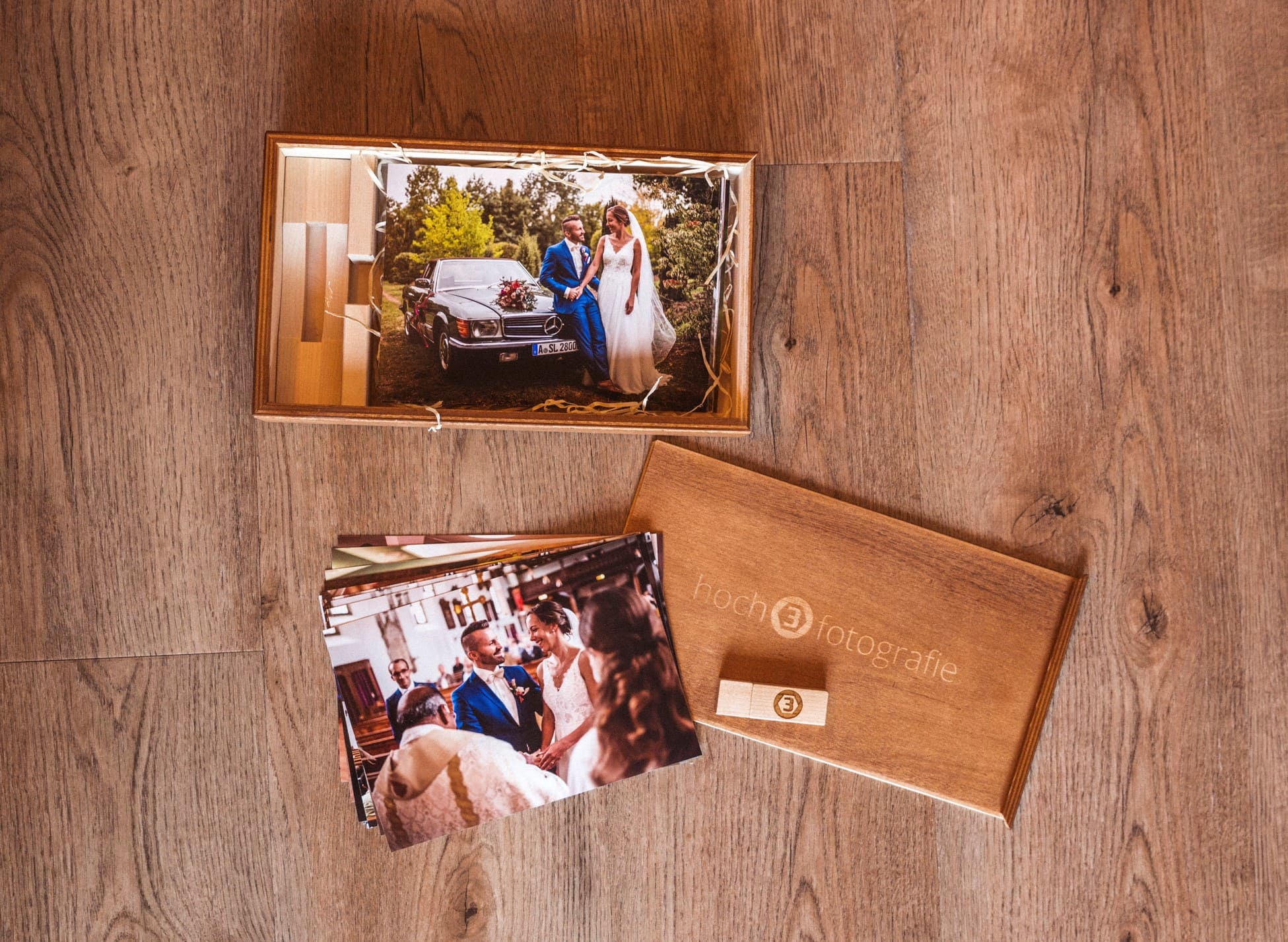Eine Nahaufnahme der geöffneten hoch3fotografie Holzbox mit den Hochzeitsbildern und USB-Stick.