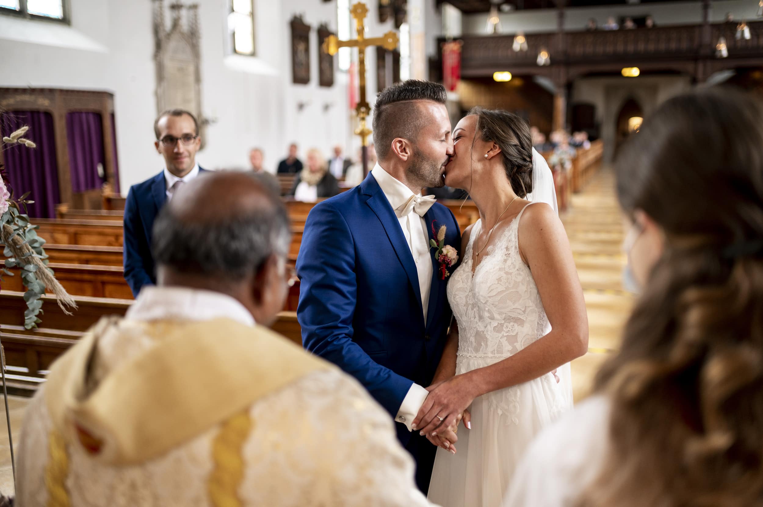 Das Hochzeitspaar küsst sich glücklich nach dem JA-Wort und Ringe Anstecken in der Kirche in Aindling.
