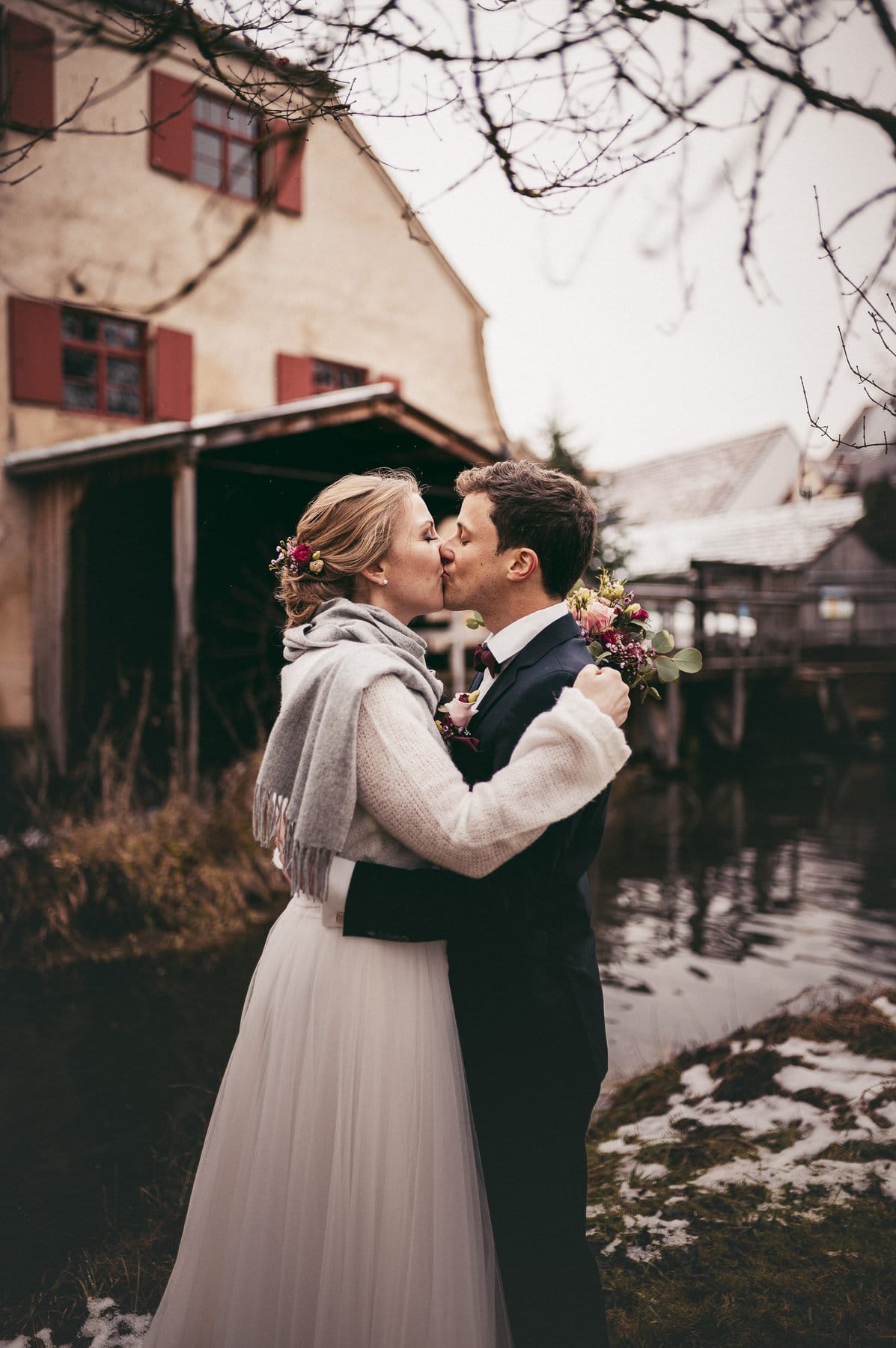 Das Brautpaar küsst sich vor der Mühle in Thierhaupten.