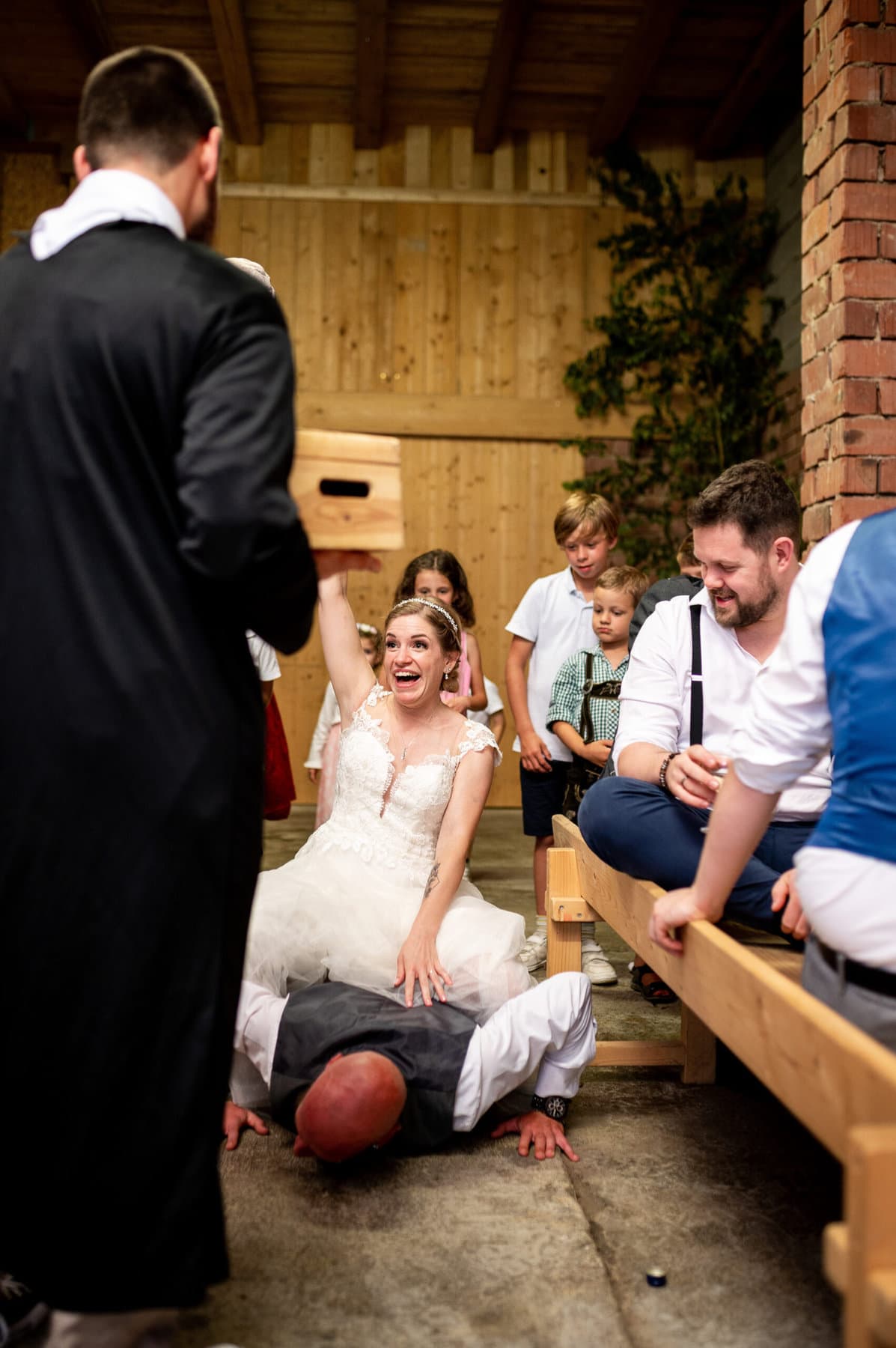 Die Braut sitzt beim Brautverziehen auf einem Mann bei der Hochzeit in Affing.
