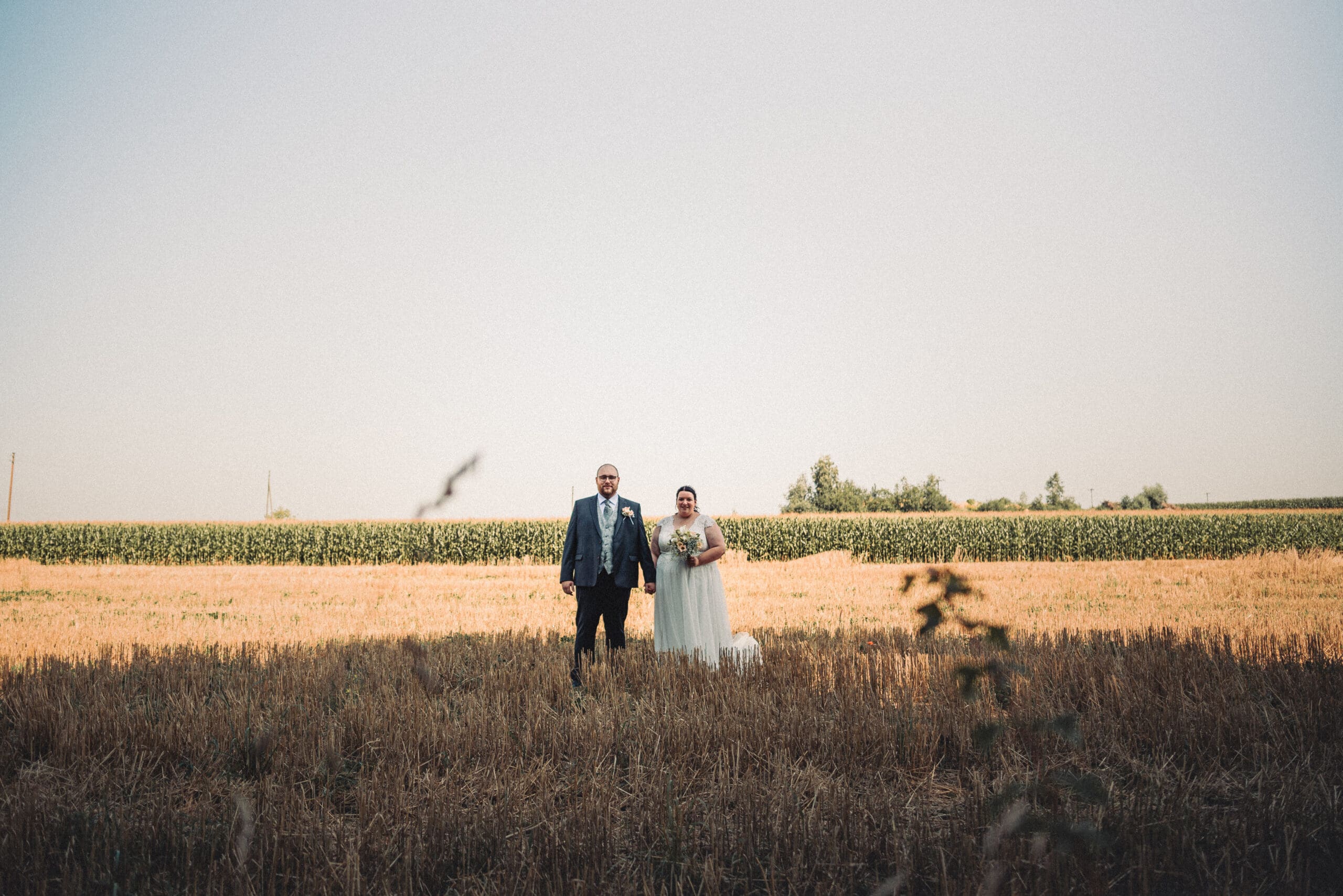 Das glückliche Brautpaar steht in einem Feld in Gablingen.