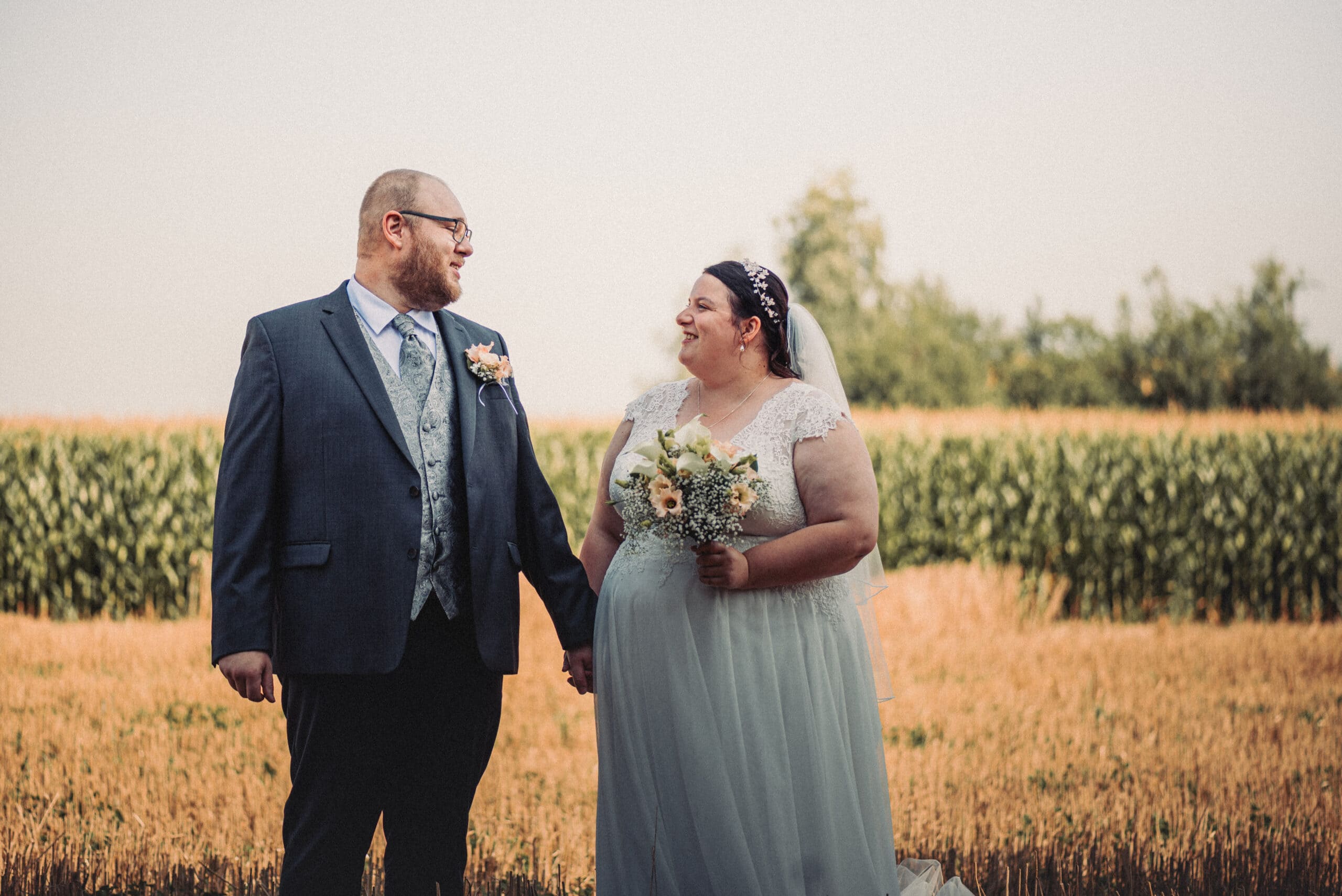 Das lachende Brautpaar beim Hochzeitsshooting in einem Feld in Gablingen.