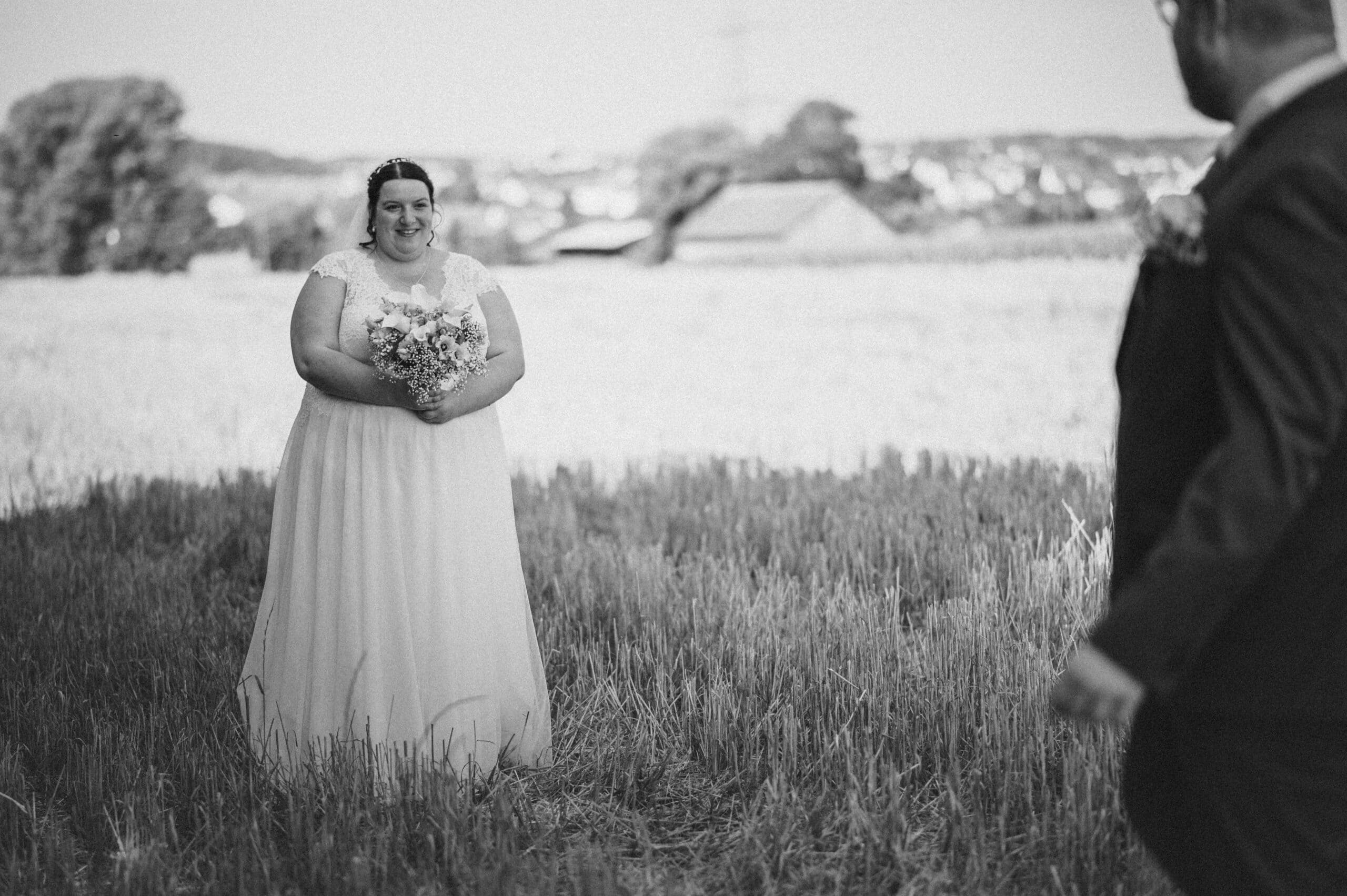 Das Brautpaar beim First-Look in einem Feld in Gablingen in schwarz-weiß.