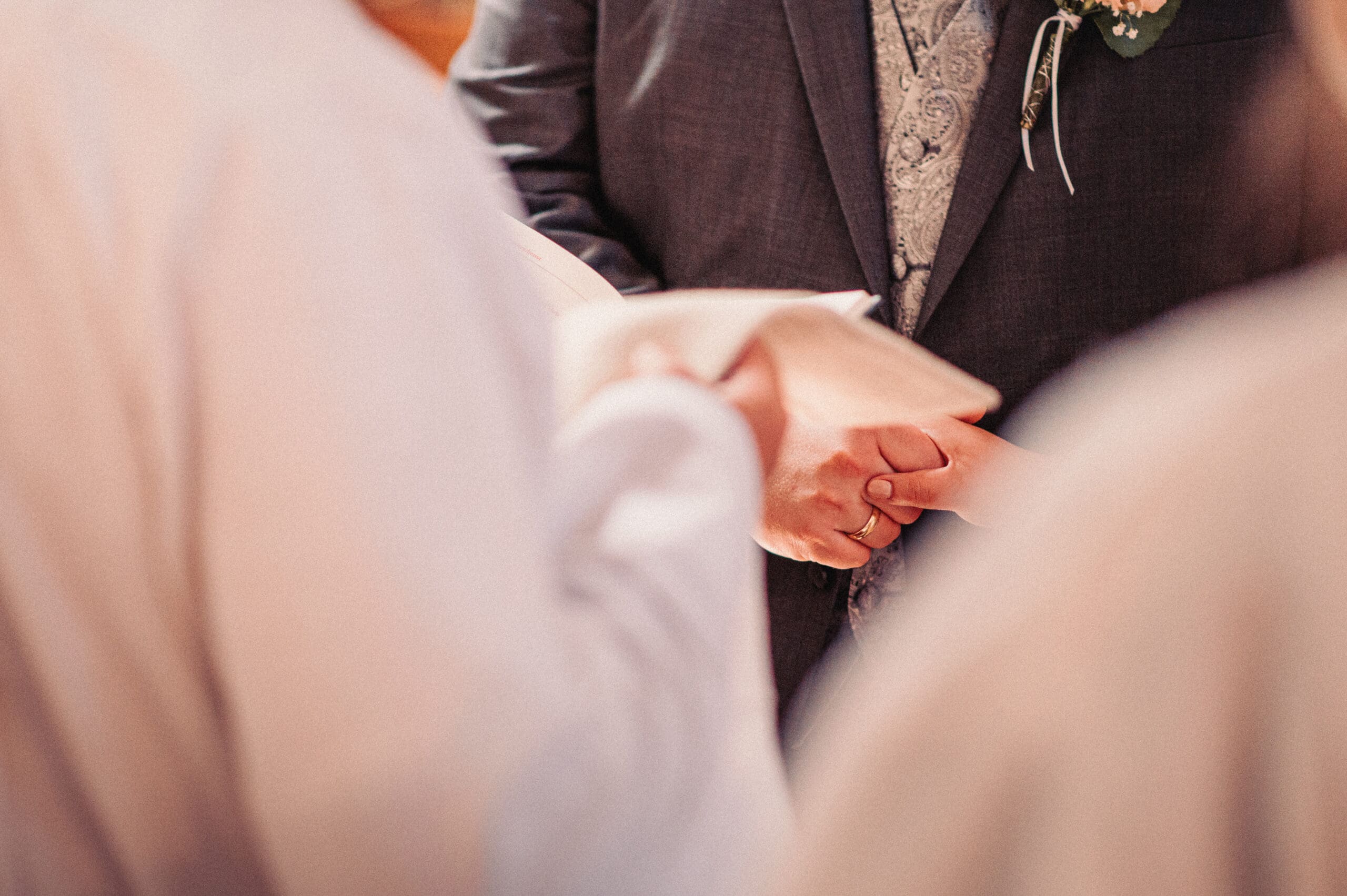 Eine Nahaufnahme wie das Ehepaar Händchen hält bei der kirchlichen Trauung in Gablingen.