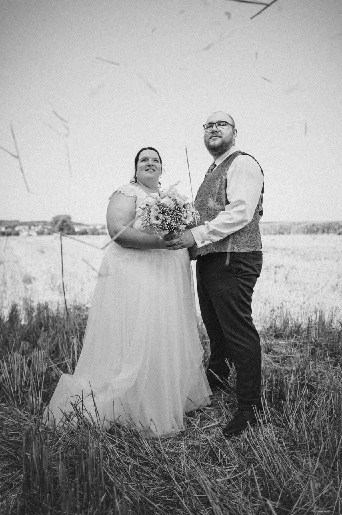 Das glückliche Brautpaar beim Hochzeitsshooting in einem Feld in Gablingen. Die Aufnahme ist in schwarz-weiß.