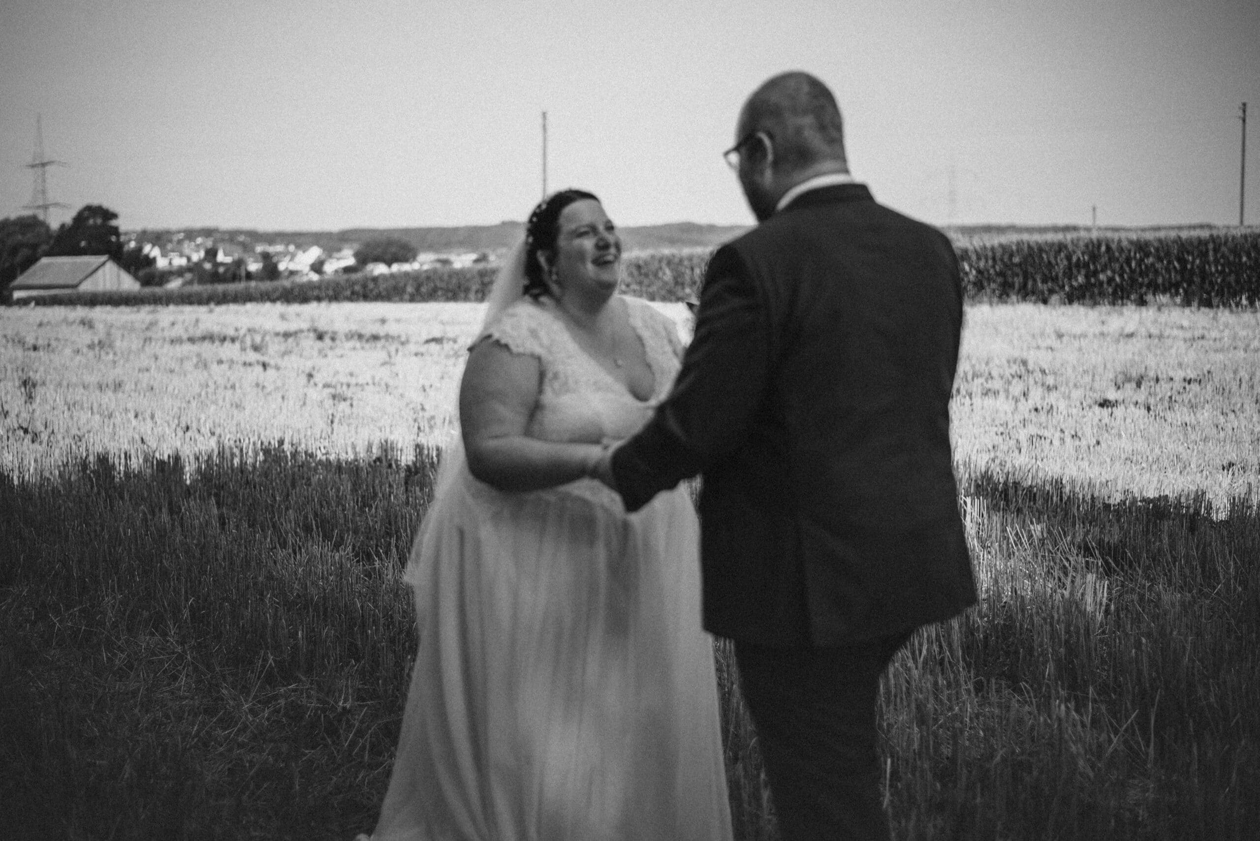 Ein überglückliches Brautpaar bei der Hochzeit in Gablingen in einem Feld.