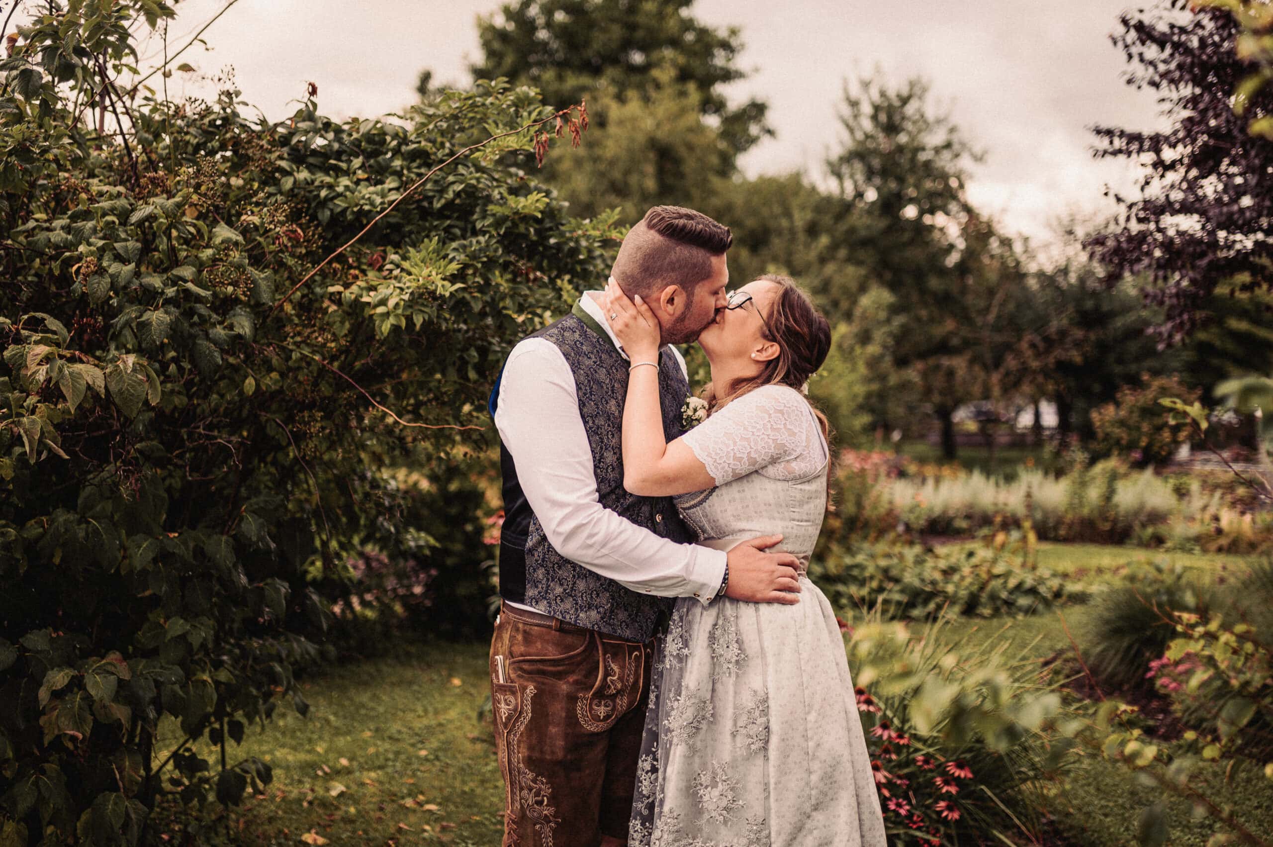 Das Brautpaar küsst sich beim Hochzeitsshooting bei der Hochzeit in Thierhaupten im Schulgarten.