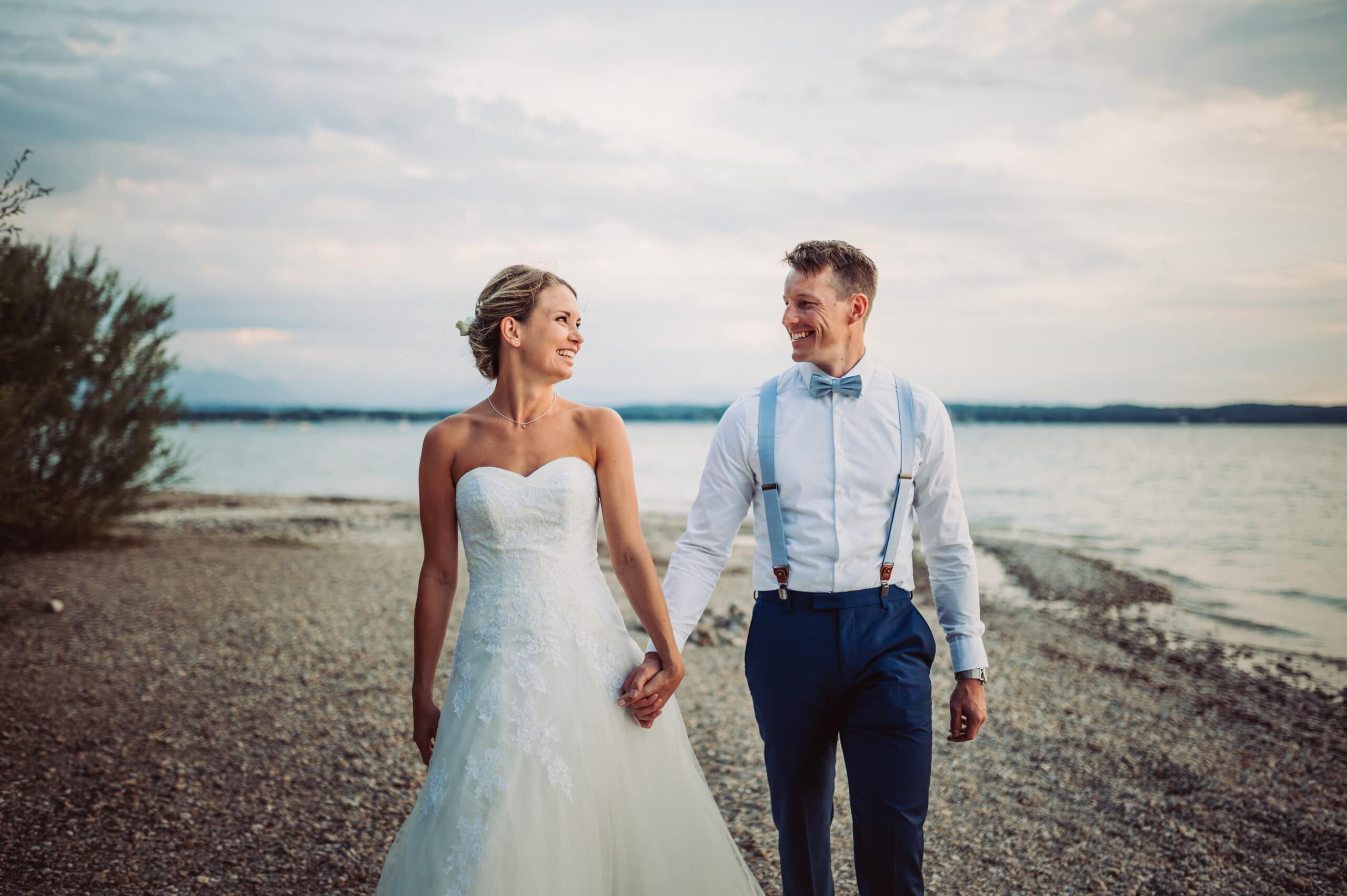 Das Hochzeitsshooting am Ufer des Starnberger Sees. Das Brautpaar spaziert glücklich am Ufer entlang.