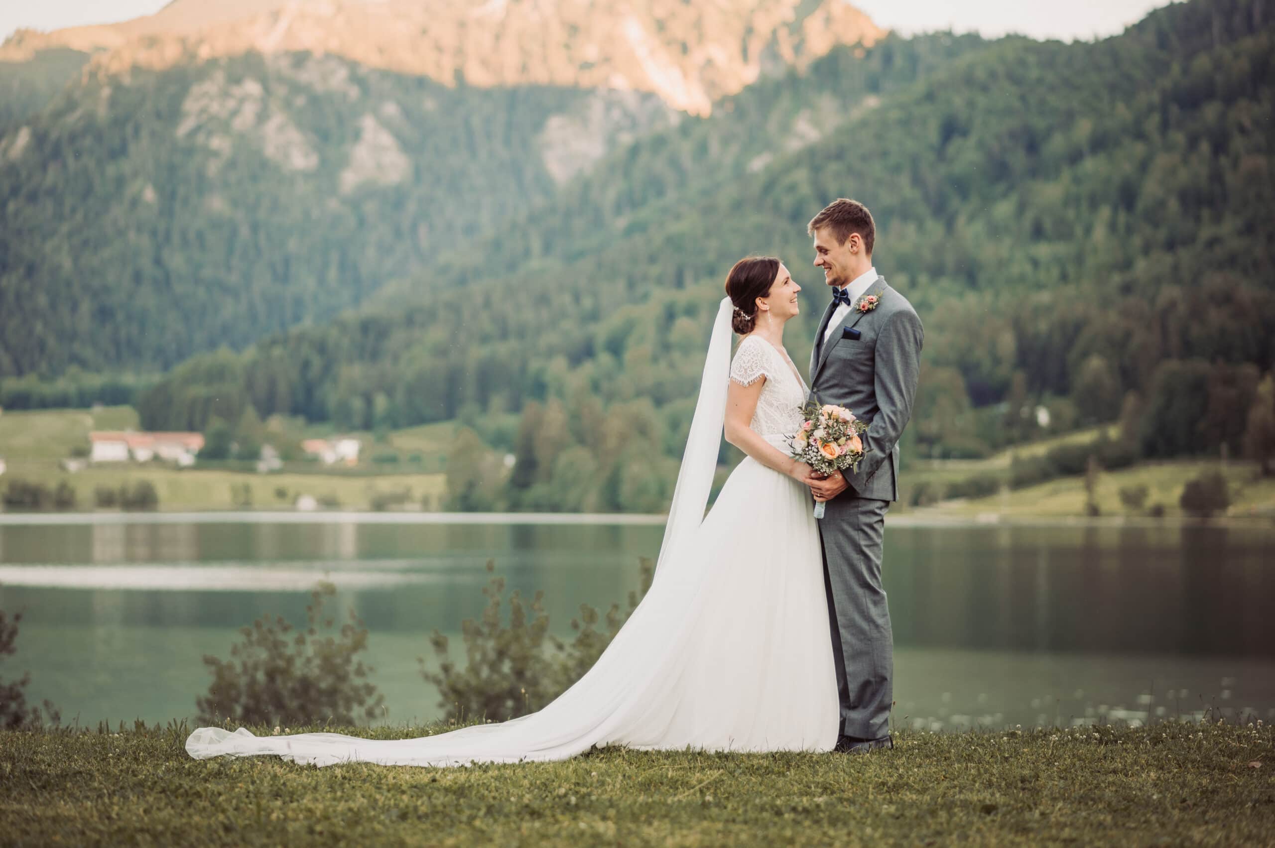 Das Hochzeitsshooting in Oberbayern am Schliersee. Das Brautpaar steht auf der Insel und sich an.