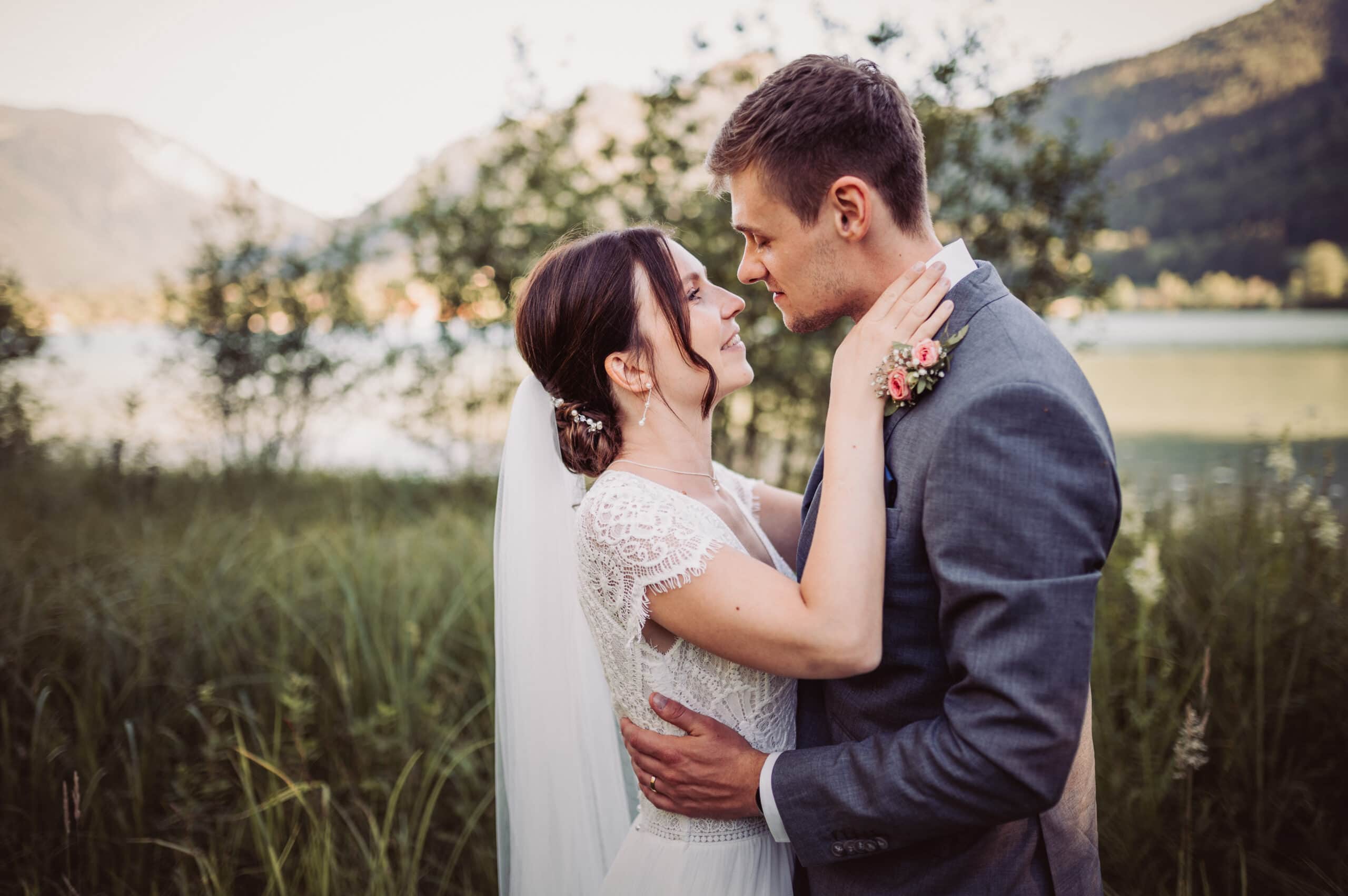 Das Hochzeitsshooting in Oberbayern am Schliersee. Das Brautpaar steht auf der Insel und ist kurz vo einem Kuss.