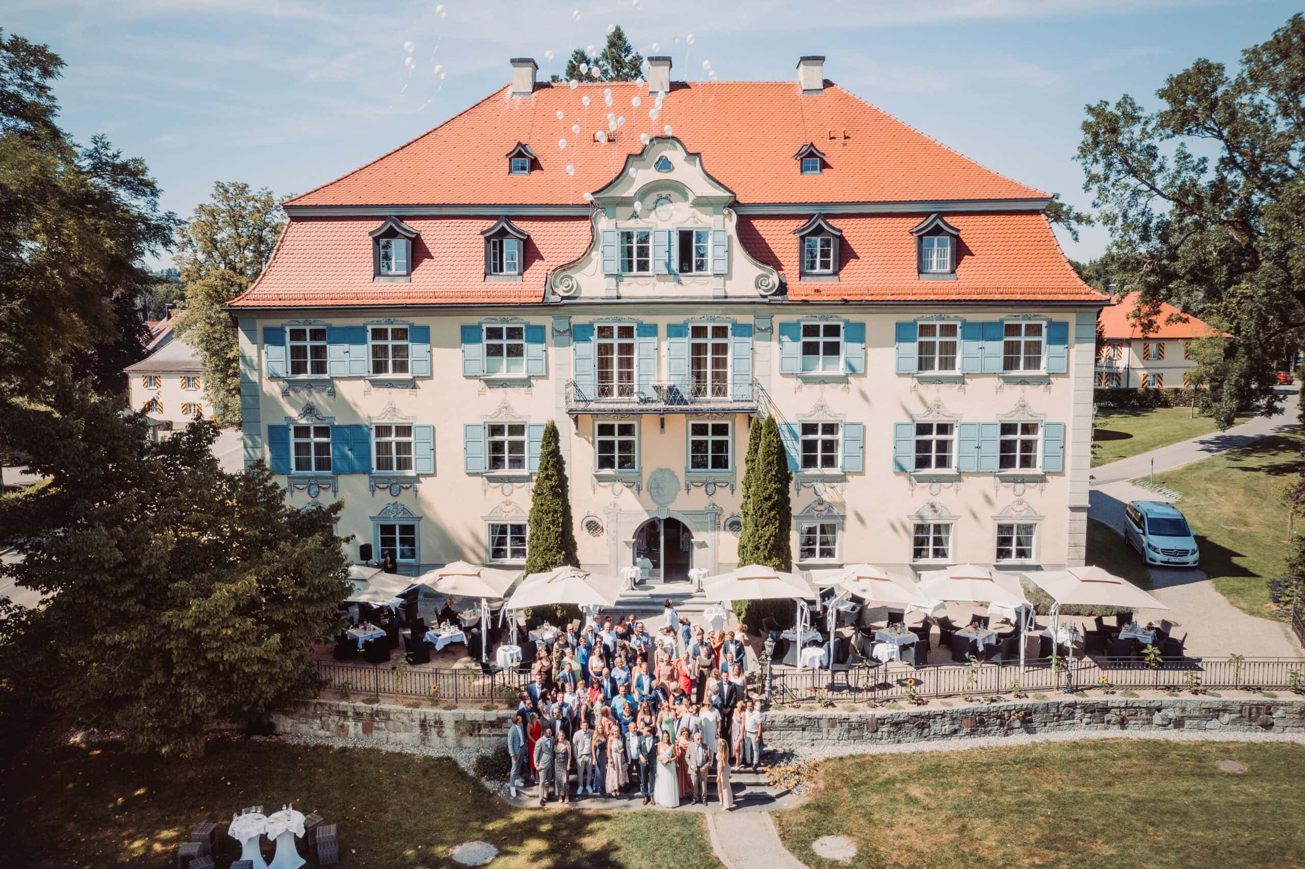 Das Gruppenshooting in Isny im Allgäu auf Schloss Neutrauchburg. Ein Gruppenbild von der Hochzeitsgesellschaft mit Luftballonen vor dem Schloss Neutrauchburg.