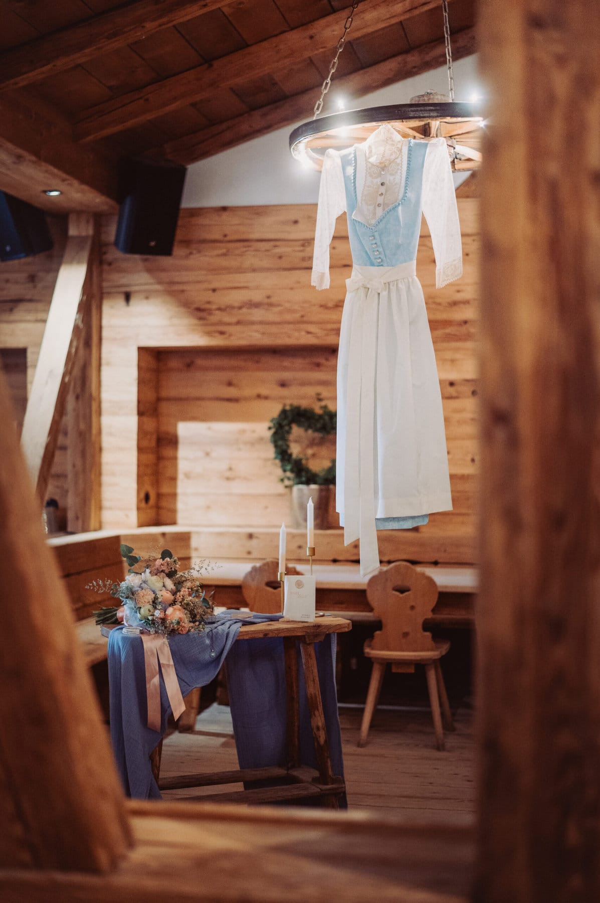 Das Getting Ready der Braut auf der Meckatzer Sportalp. In einem Raum aus Holz hängt das Shooting-Kleid der Braut. Nebenan steht ein Beistelltisch mit ihrem Brautstrauß.