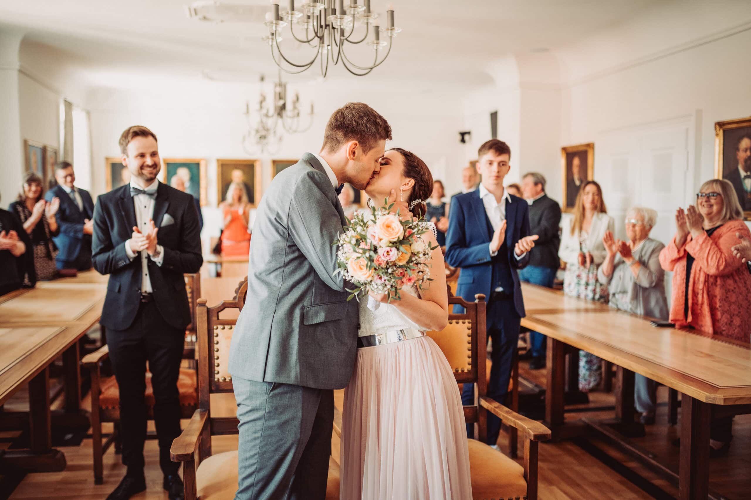 Das Standesamt in Oberbayern am Schliersee. Das Brautpaar küsst sich bei der Trauung und die Gäste klatschen.