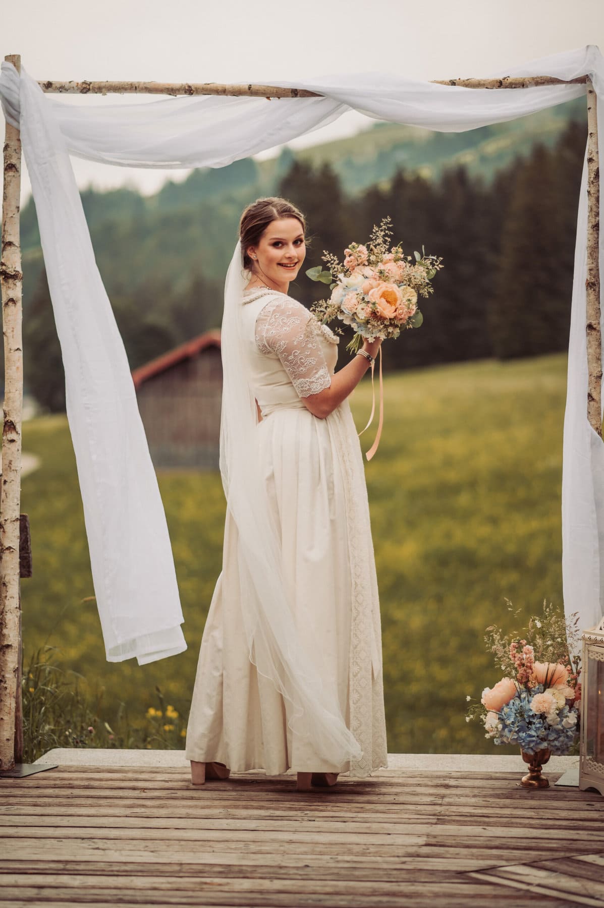 Die Trauung auf der Meckatzer Sportalp. Die Braut mit ihrem Brautstrauß in der Hand unter dem Bogen.