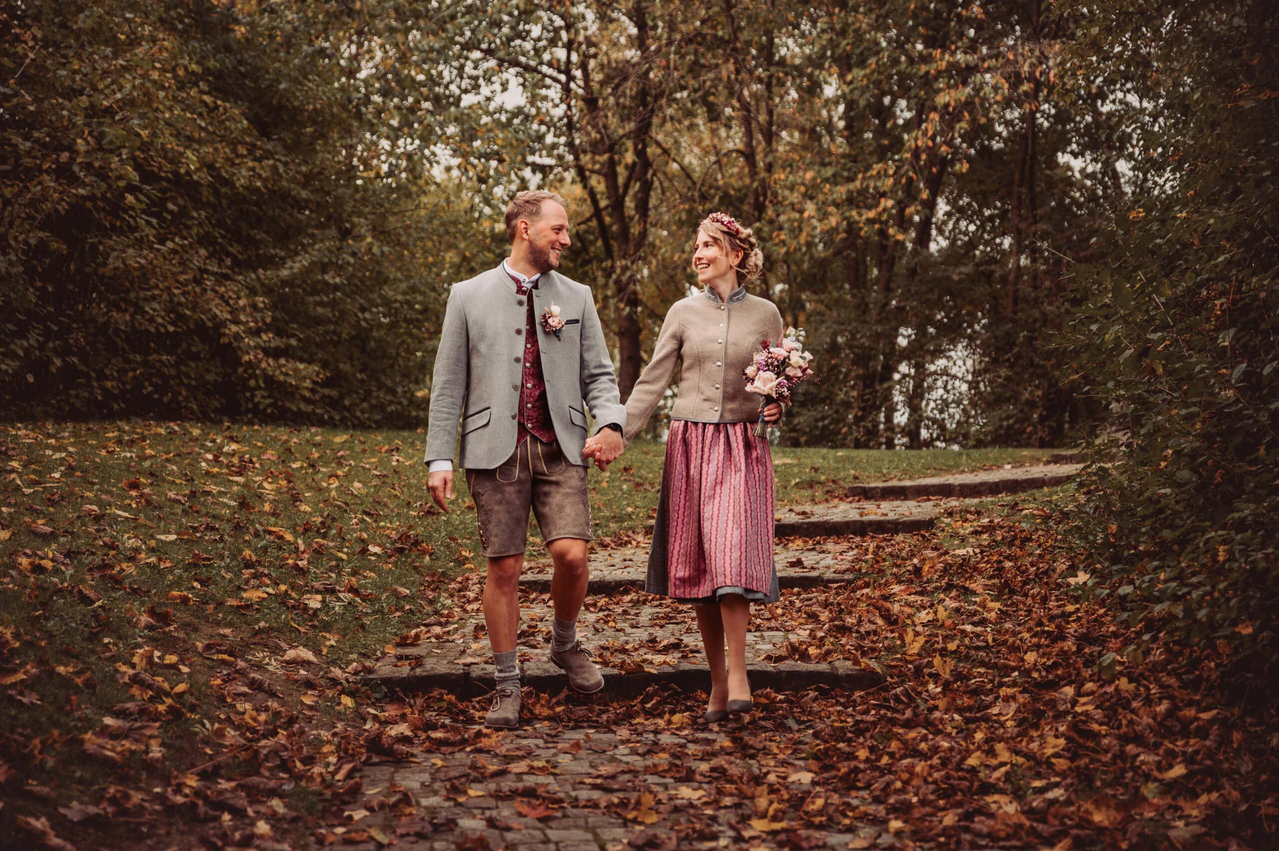 Brautpaar spaziert durch bunte Blätter im Herbst