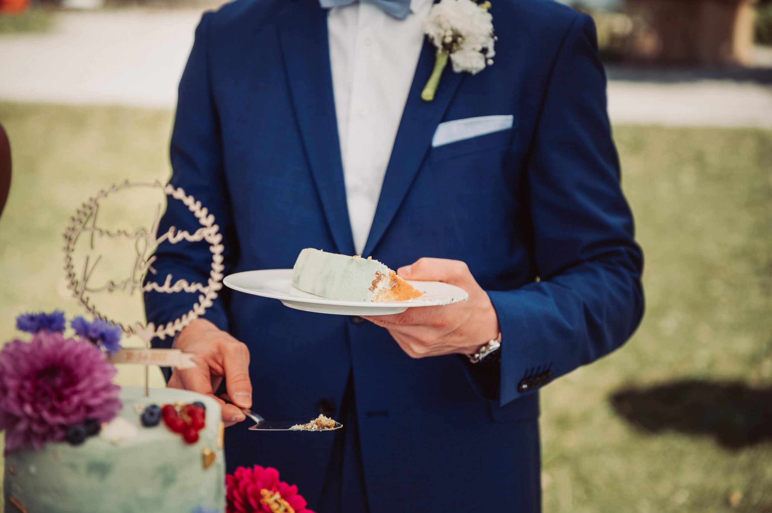 Der Bräutigam mit einem Stück der Hochzeitstorte in der Hand bei der Hochzeitsfeier am Starnberger See im Garten vom Seewirt Buchscharner