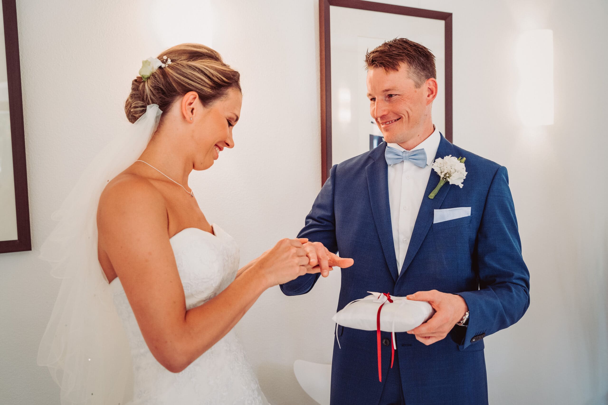 Die Braut steckt dem Bräutigam den Ehering bei der Hochzeit im Standesamt in Pöcking an.