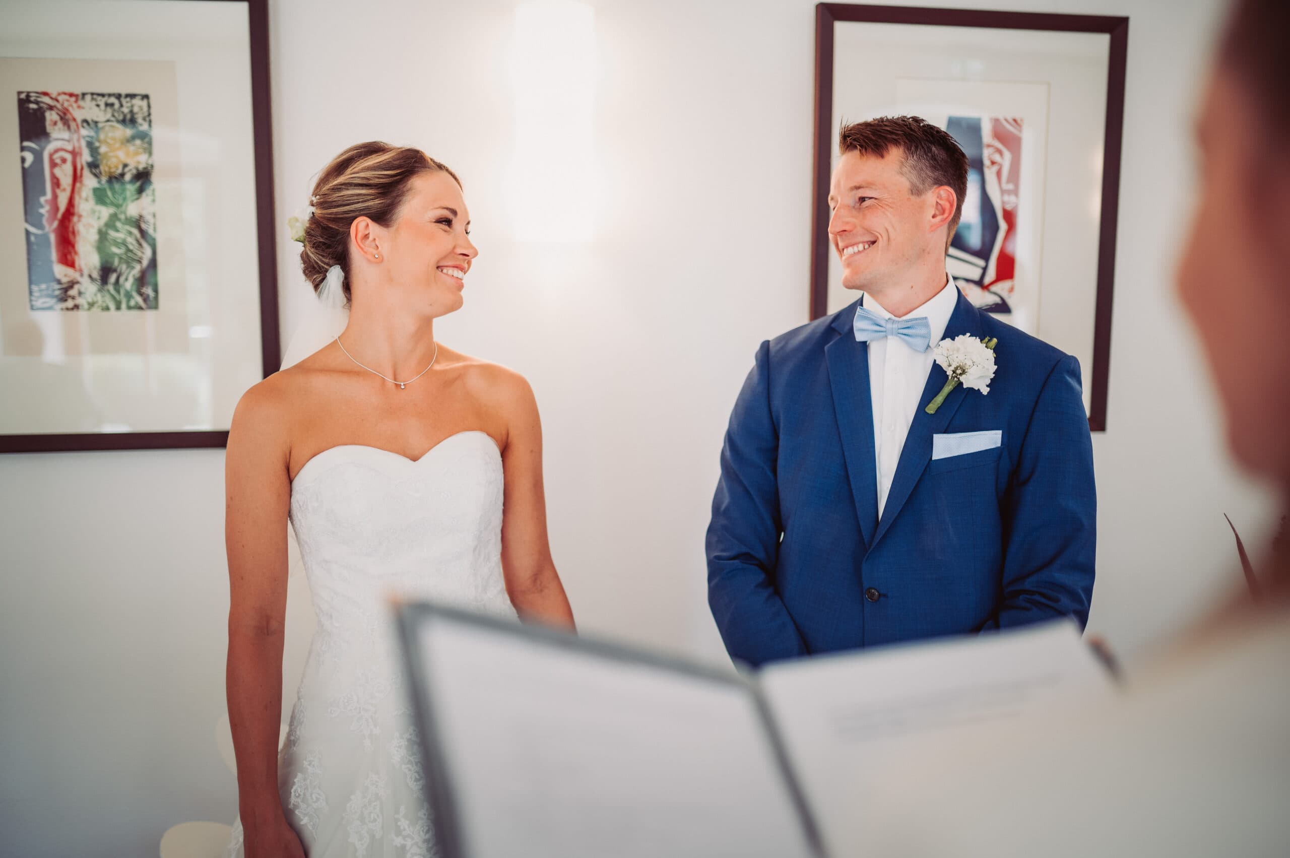 Das Brautpaar sieht sich während der standesamtlichen Hochzeitsfeier in Pöcking lächelnd an.