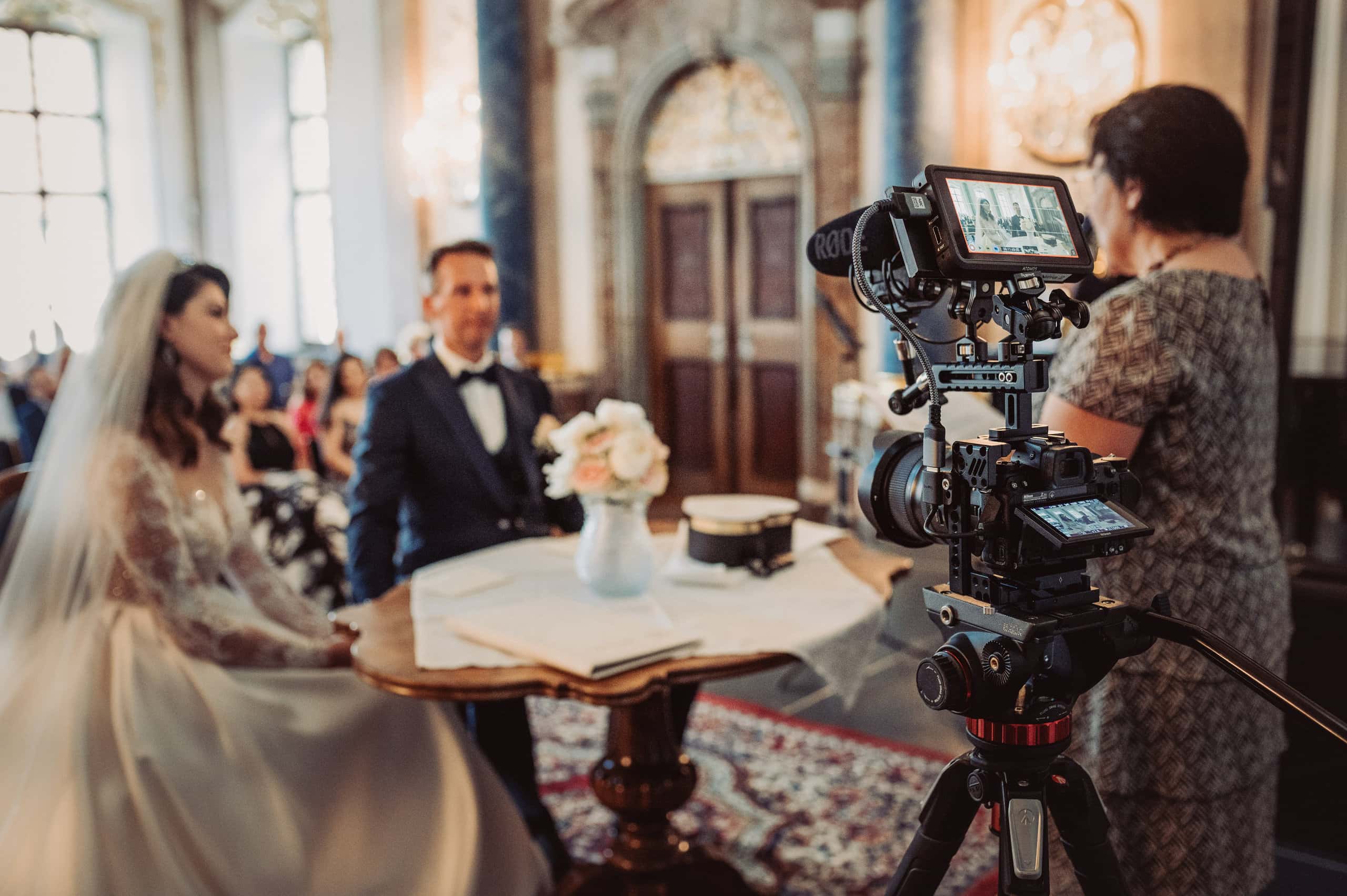 Eine Videokamera gerichtet auf ein Brautpaar im Standesamt für eine Filmaufnahme.
