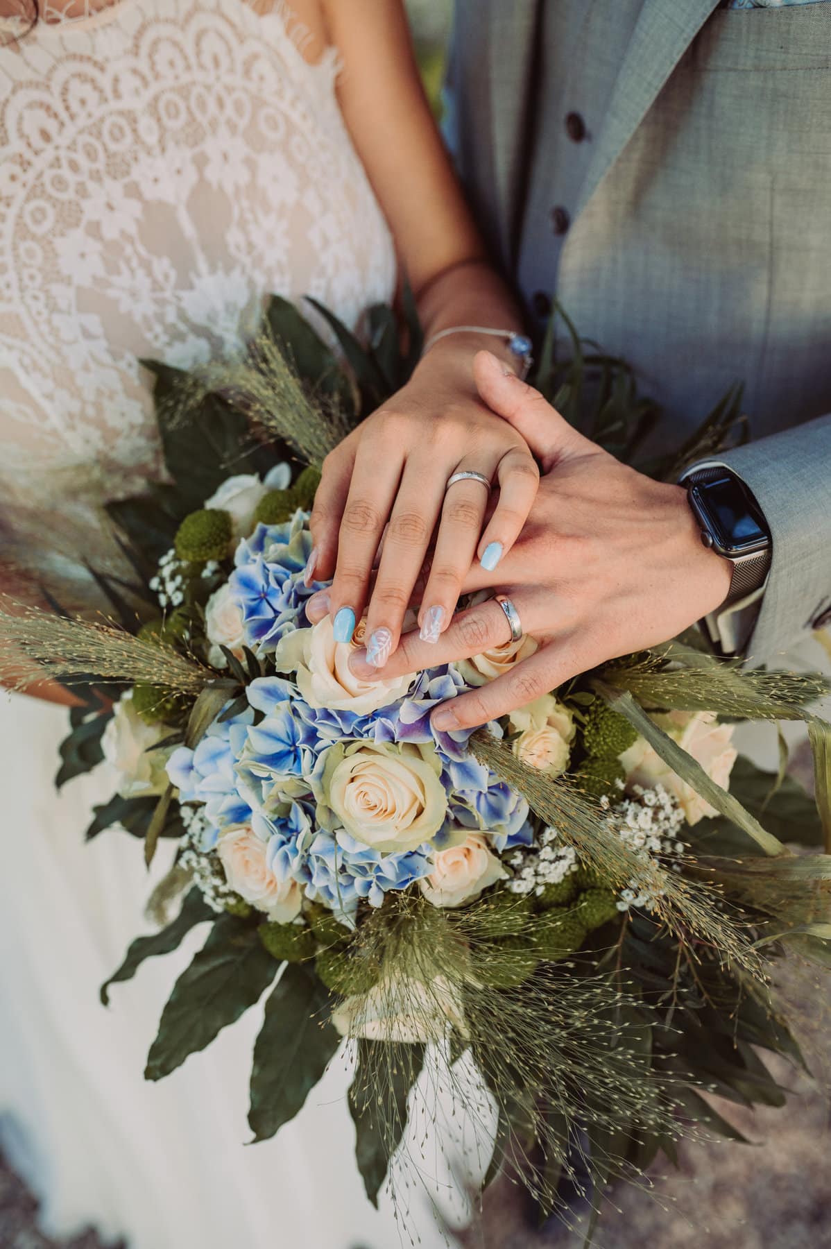 Hände auf Brautstrauß mit passenden Eheringen