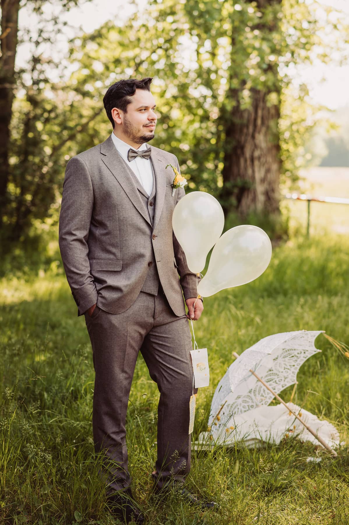 Bräutigam steht und hält Luftballons in der Hand